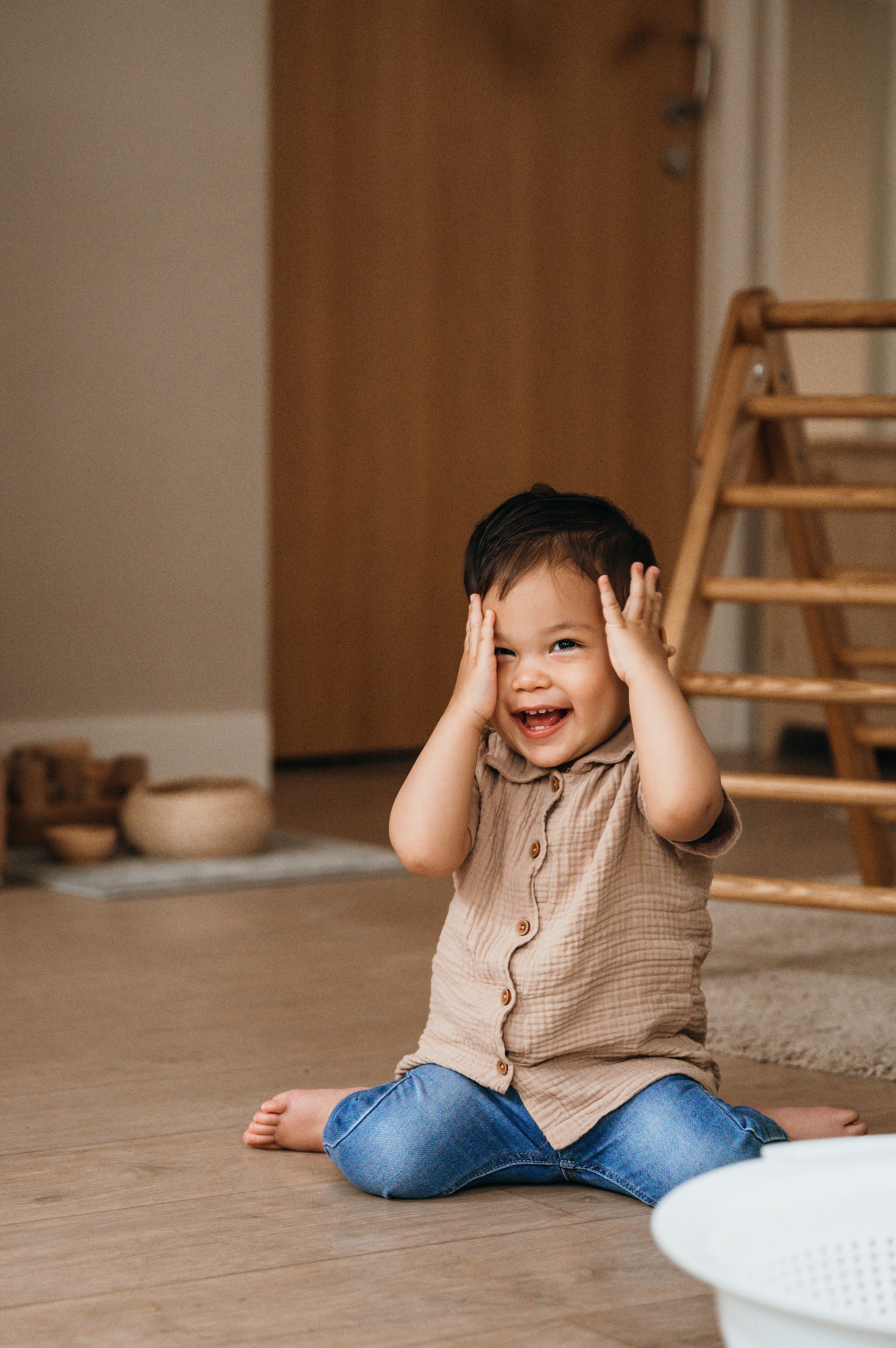 jongen lacht en zit op de grond met handen voor zijn ogen
