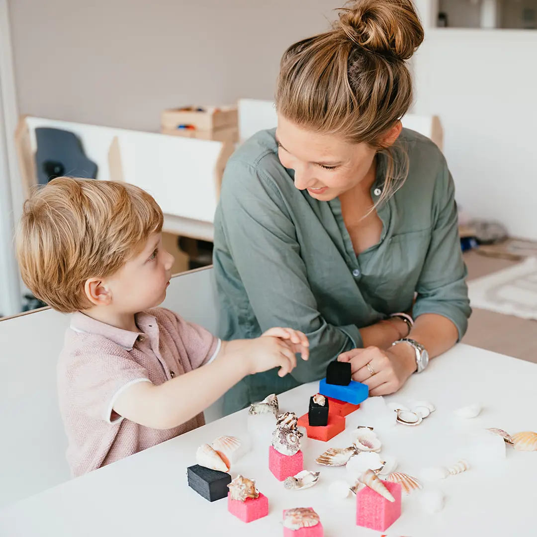 Werken bij CompaNanny Pedagogisch Medewerker en kind spelen met schelpen