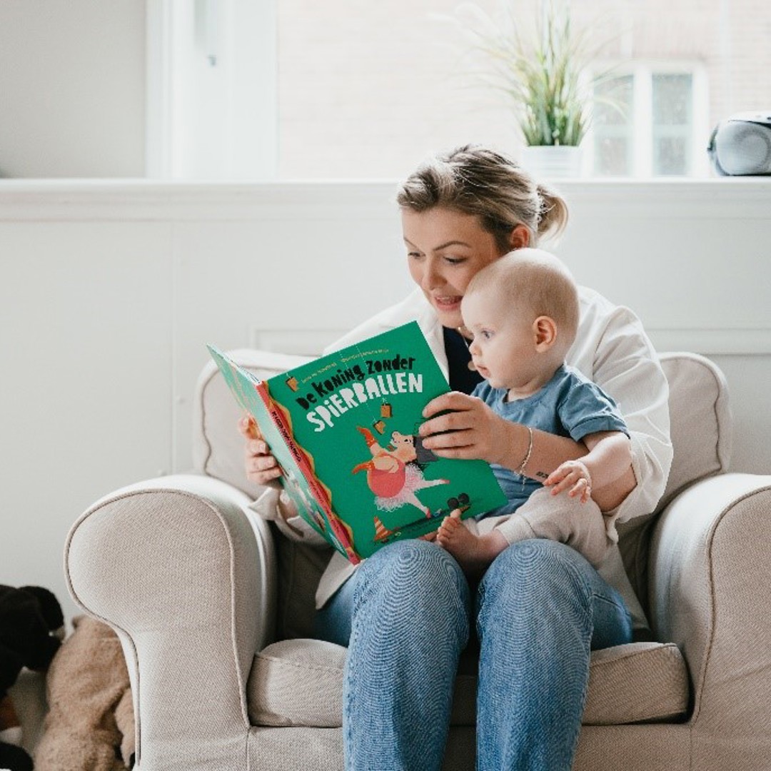 Pedagogisch Medewerker lees boek voor aan baby op kinderopvang