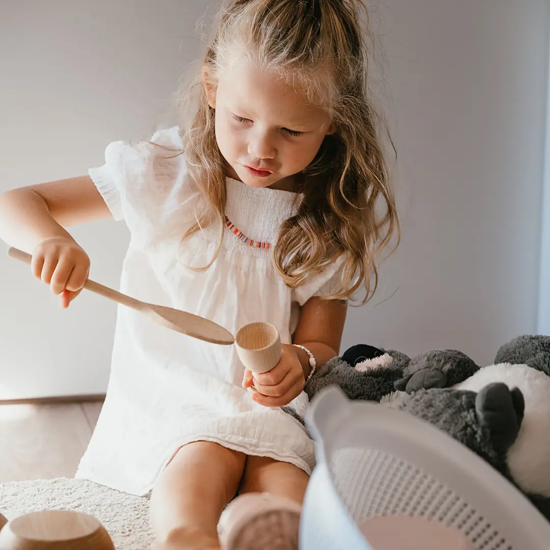 Werken bij CompaNanny kind speelt met houtenlepel