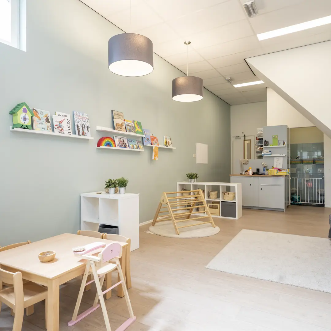 babygroep binnenruimte kinderopvang met spelmateriaal klimtoestel tafel stoelen en bank