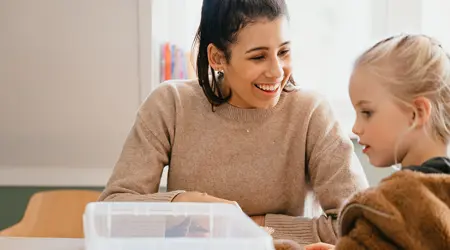 Vrouw speelt met kind aan tafel