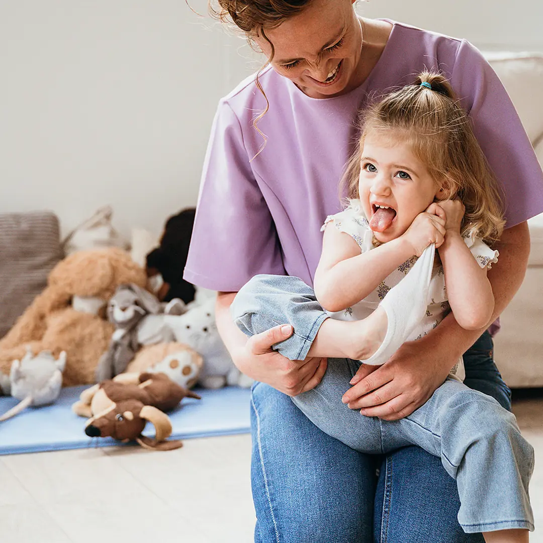 Meisje zit op schoot bij vrouw en trekt sok uit