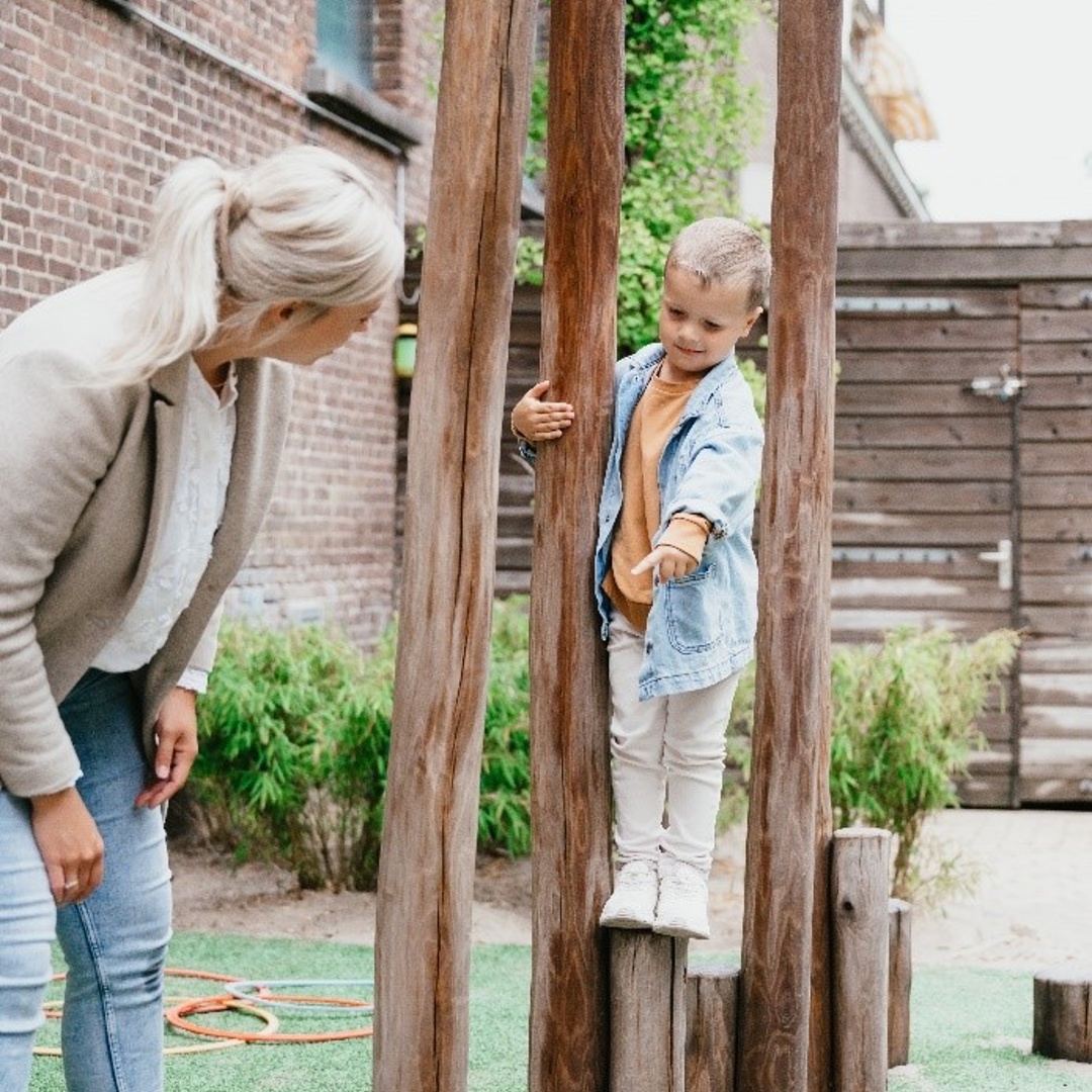 Pedagogisch Medewerker en kind buiten spelen